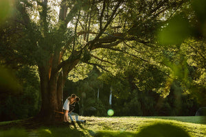surprise engagement photo of couple under giant tree and swing
