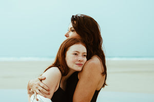 mother and daughter embrace on beach lifestyle photoshoot